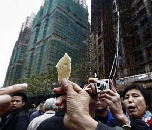 居民舉著起火大樓外墻的保溫材料,認(rèn)為它并沒有阻燃性。