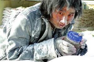 一名工人抱著水杯在成品大白粉堆上發呆